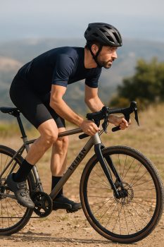 Cycliste en tenue de gravel roulant sur un chemin sec avec le vélo Triban GRVL 900 en titane