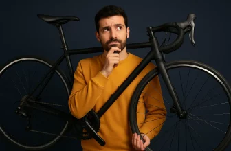 Homme pensif tenant un vélo dans les mains, illustrant la recherche de la bonne taille de cadre.